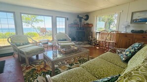 Una sala de estar con sofá, sillones, chimenea y vistas al océano.
