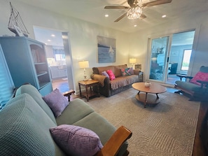 A living room with a sofa, a coffee table, a bookshelf, and a dining area visible through a glass door. - East Shore - Lake View Cottage - Pelee Island (Pelee)