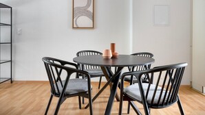 Un comedor con una mesa redonda, cuatro sillas y una obra de arte abstracta enmarcada en la pared.