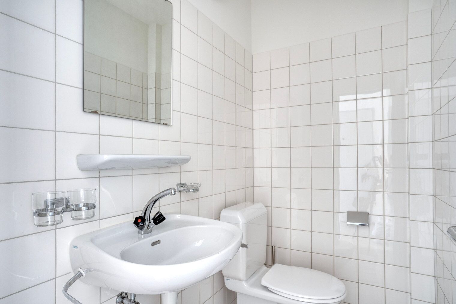 Une salle de bain avec un lavabo blanc, un miroir et des toilettes.