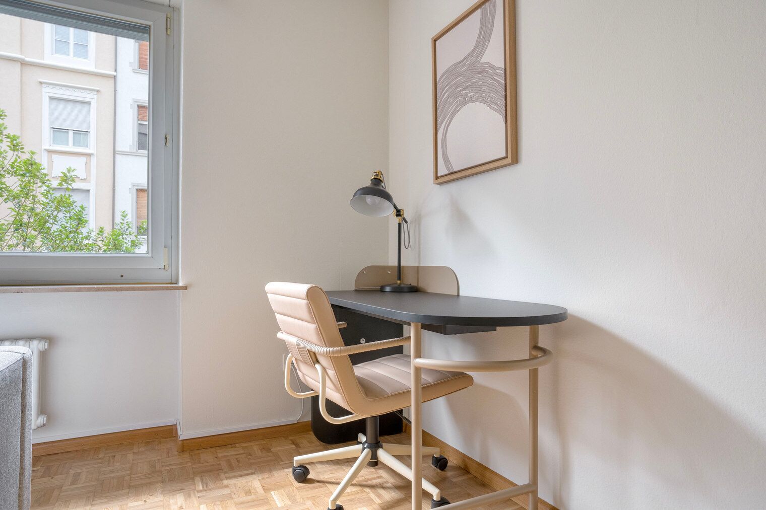 A corner office with a desk, chair, and a desk lamp.