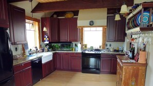 Cucina spaziosa con pensili e basi in legno scuro, un'isola centrale e un piano cottura.