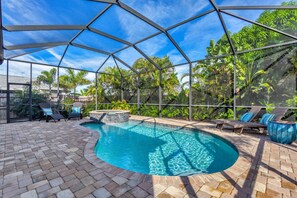A covered outdoor swimming pool with lounge chairs and a hot tub, surrounded by lush greenery. - Casa Aria is an tropical retreat complete with all the amenities for a luxurious beach vacation! (Naples)