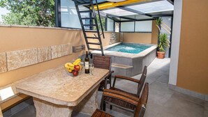 Eine Terrasse mit Tisch, Stühlen, einer Leiter, einem Whirlpool und einem Blumentopf.