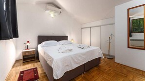 Ein Schlafzimmer mit einem Bett, einem Nachttisch, einer Lampe, einer Klimaanlage und einem Spiegel an der Wand.