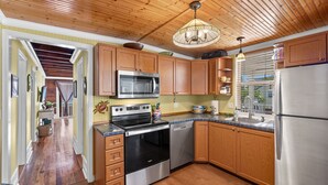 Una cocina con armarios de madera, electrodomésticos de acero inoxidable y techo de madera.
