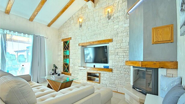 Un salon moderne avec un mur en pierre, un téléviseur à écran plat, une cheminée et un canapé confortable.