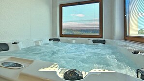 Un bain à remous avec une fenêtre donnant sur l’extérieur, un panneau de commande et un siège intégré.