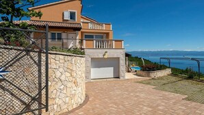 A two-story house with a stone wall, a garage, and a pool. - Stunning home in Brsec with sauna (Brsec)