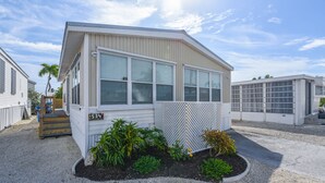 A single-story building with a sloped roof, large windows, and a small porch. - Venture Out 2 Bedroom (Cudjoe Key)