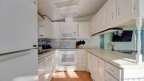 A kitchen with white cabinets, a microwave, stove, and a sink. - Venture Out 2 Bedroom (Cudjoe Key)