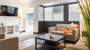 A modern living room with a sofa, coffee table, and TV. - Bello Monte Retreat House with Pool in El Yunque (Hato Candal)