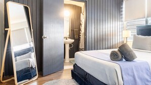 A modern bedroom with a large bed, a bedside mirror, and a view of the bathroom. - Bello Monte Retreat House with Pool in El Yunque (Hato Candal)