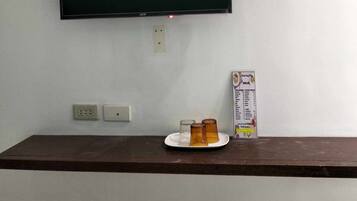 A television mounted on a wall, a power outlet, and a small table with a plate and a menu.