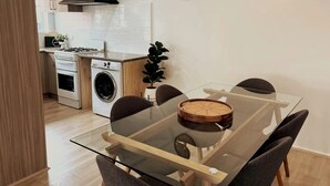 Una cocina moderna con estufa a gas, horno y lavadora, una mesa de comedor con sillas y un reloj en la pared.