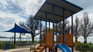 Un parque infantil con un tobogán, escaleras de acceso y una zona de juegos cubierta.