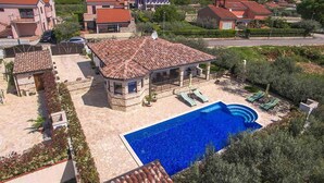 Zona residencial com piscina, edifícios de pedra e vista ampla da paisagem ao redor.