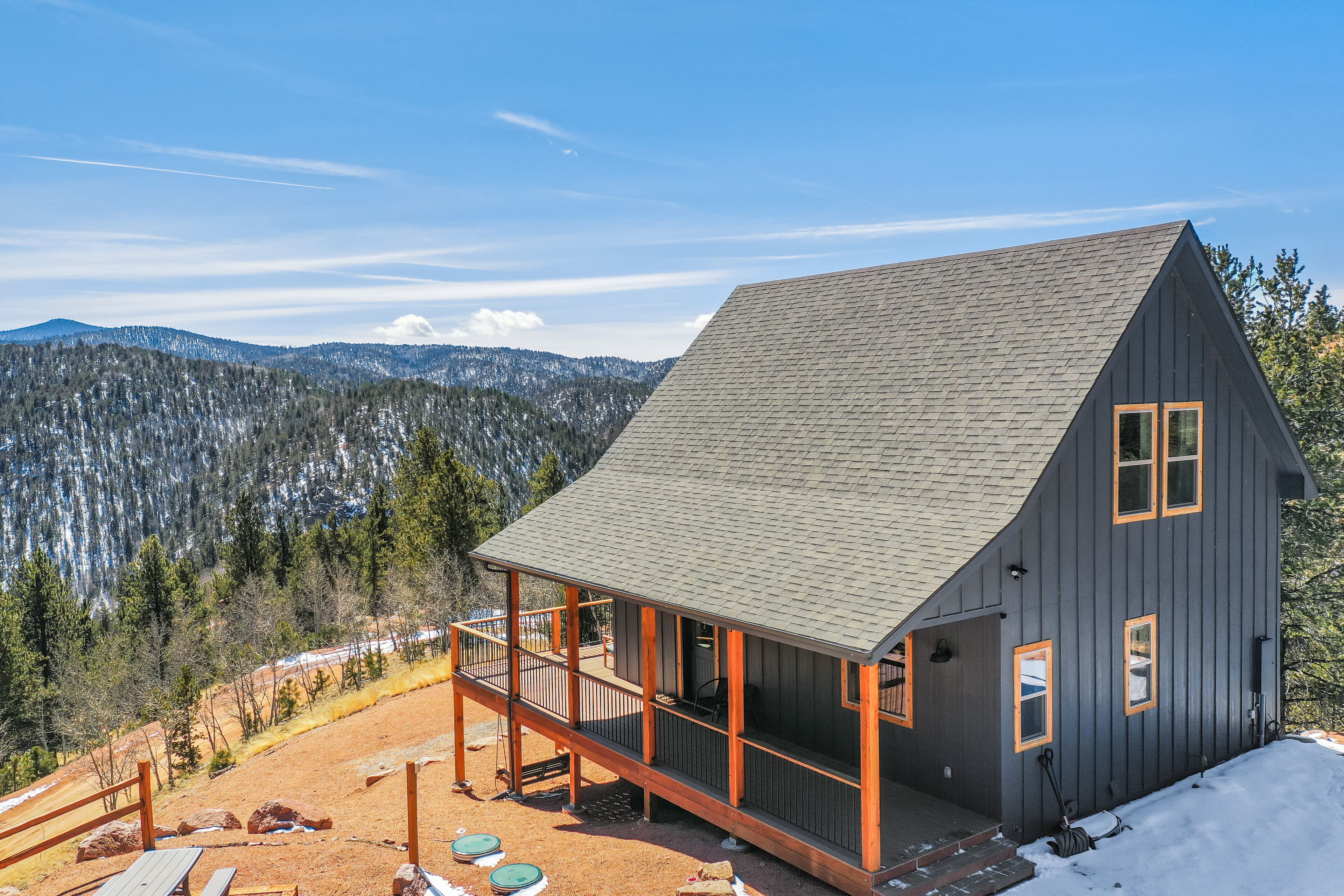 A cabin with a balcony, surrounded by a mountainous landscape.
