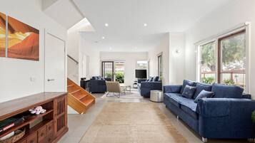 A spacious living room with a sofa set, a TV, and a staircase leading to another room.