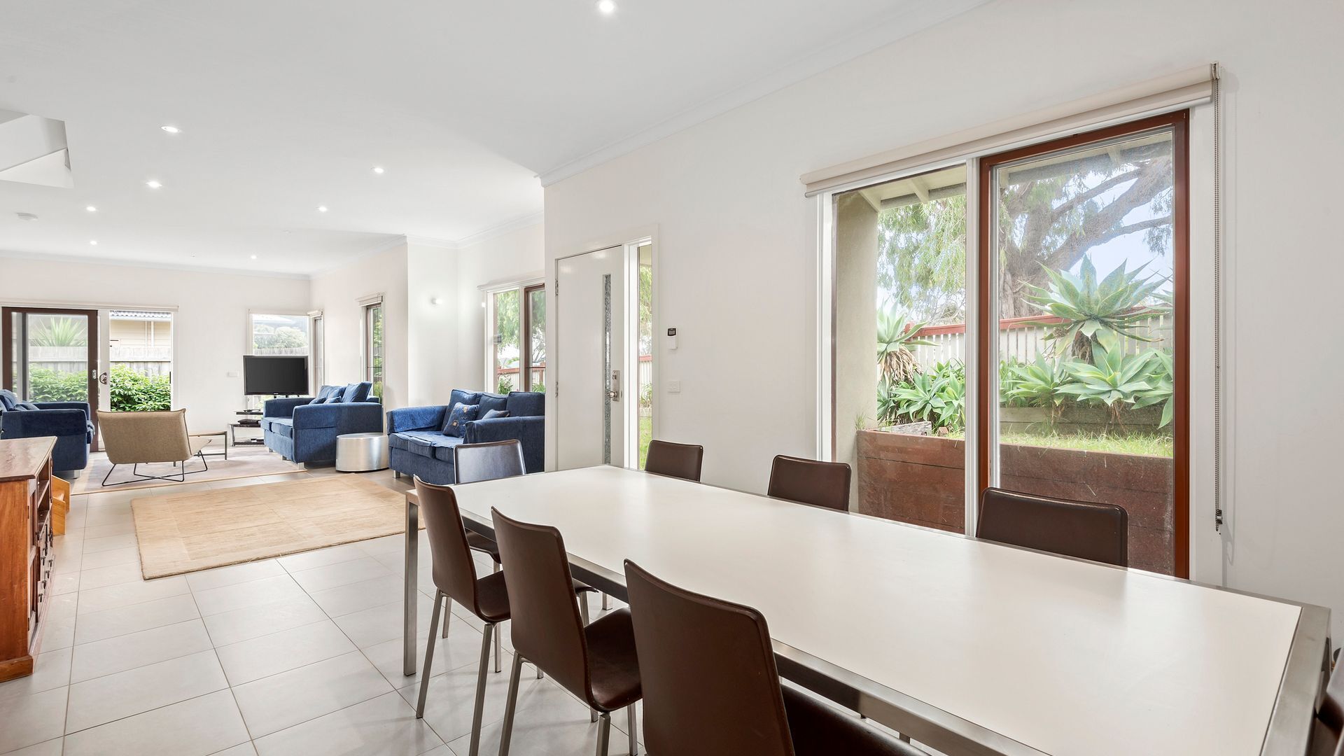A spacious living area with a dining table, sofas, and a TV.