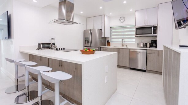 Een moderne keuken met een centraal eiland, roestvrijstalen apparatuur en witte kasten.