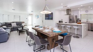 Een moderne keuken met een houten keukeneiland, barstoelen en een eettafel voor vier personen.