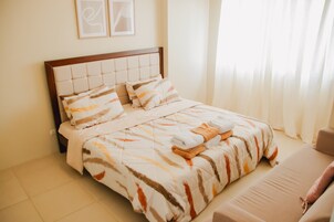 A neatly made bed with a striped bedspread, a headboard, and a pillow.