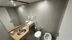Et moderne badeværelse med vask, toilet, bidet og håndklædestang.
