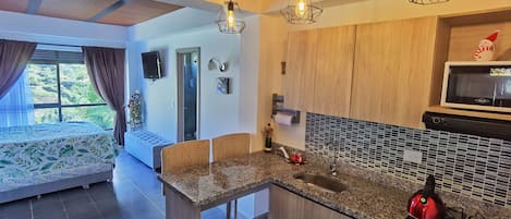 A modern kitchen with a granite countertop, a red kettle, and a microwave.