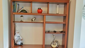 Un bureau en bois doté de plusieurs étagères, d’un petit meuble de rangement et d’objets décoratifs, notamment un gnome, un cerf et un vase rempli de fleurs.