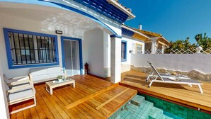 Une villa moderne dotée d’une terrasse en bois, d’une piscine et d’un espace salon extérieur abrité.