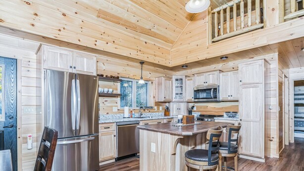 Una cocina moderna con armarios de madera, electrodomésticos de acero inoxidable y una isla central con taburetes de bar.