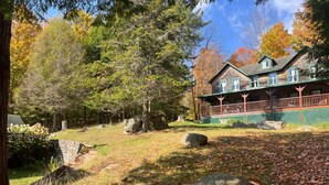 Un chalet rustique doté d’une véranda, entouré d’arbres et de rochers.