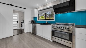 Una cocina moderna con estufa de acero inoxidable, horno integrado y ventana con vistas al exterior.