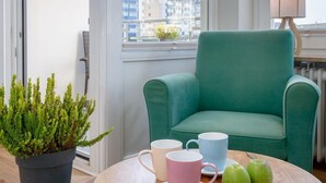A balcony with a green armchair, a wooden table with green apples and pink cups, and a potted plant. - Wohnung Stella - Am Strand- Wohnung Stella (Westerland)