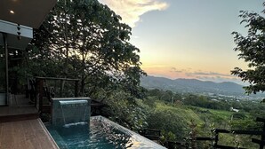 An infinity pool with a view of a landscape and distant mountains.