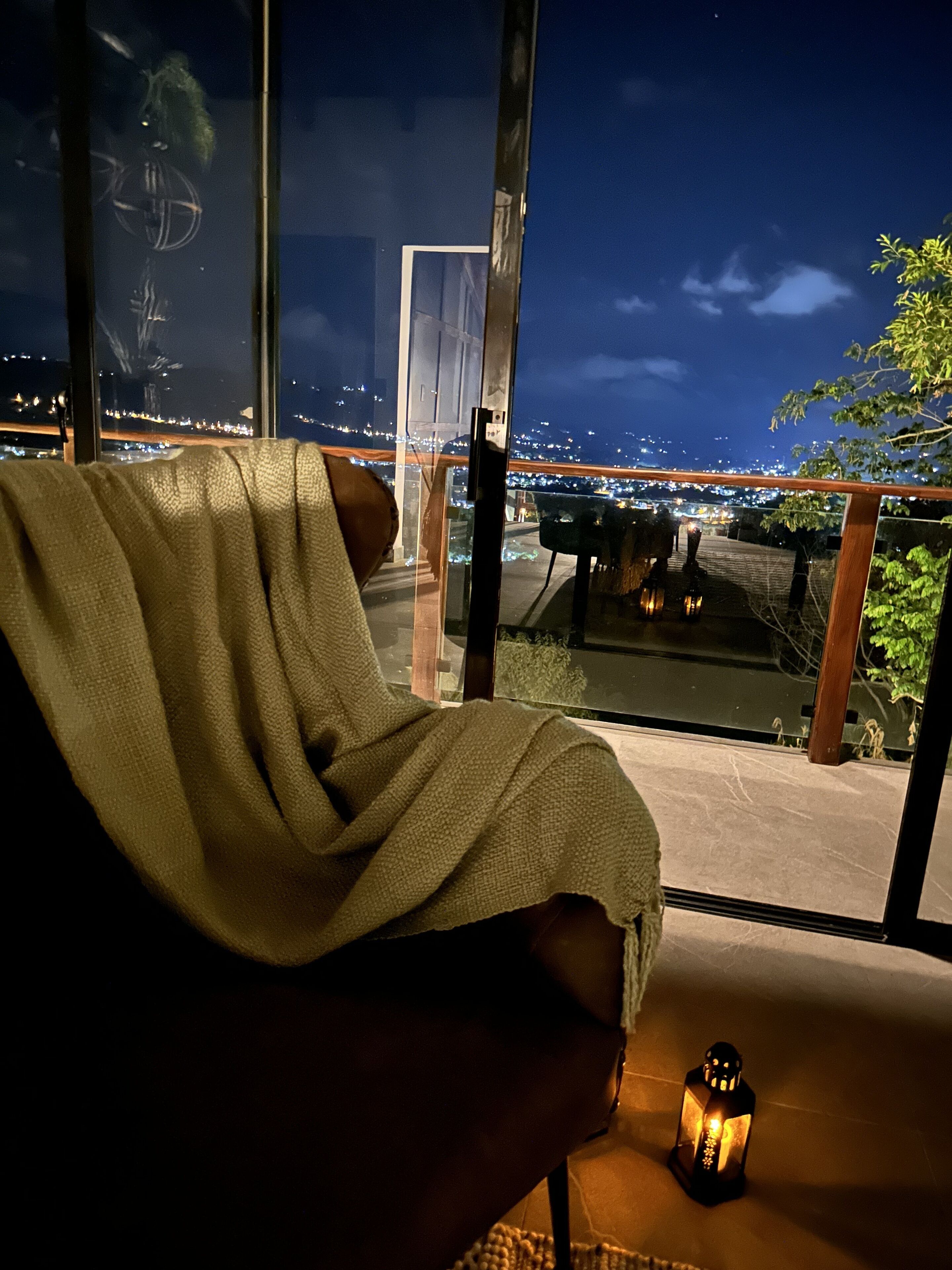 A room with a large window overlooking a cityscape at night.