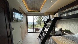 A modern bedroom with a bunk bed, a TV mounted on the wall, and a sliding glass door leading to an outdoor area.