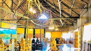 A spacious indoor area with a high ceiling and thatched roof. There are several wooden chairs and tables arranged for seating. - Eco Mara Tented Camp  (Maasai Mara)