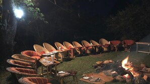 An outdoor seating area with wicker chairs and tables, arranged around a fire pit. - Eco Mara Tented Camp  (Maasai Mara)