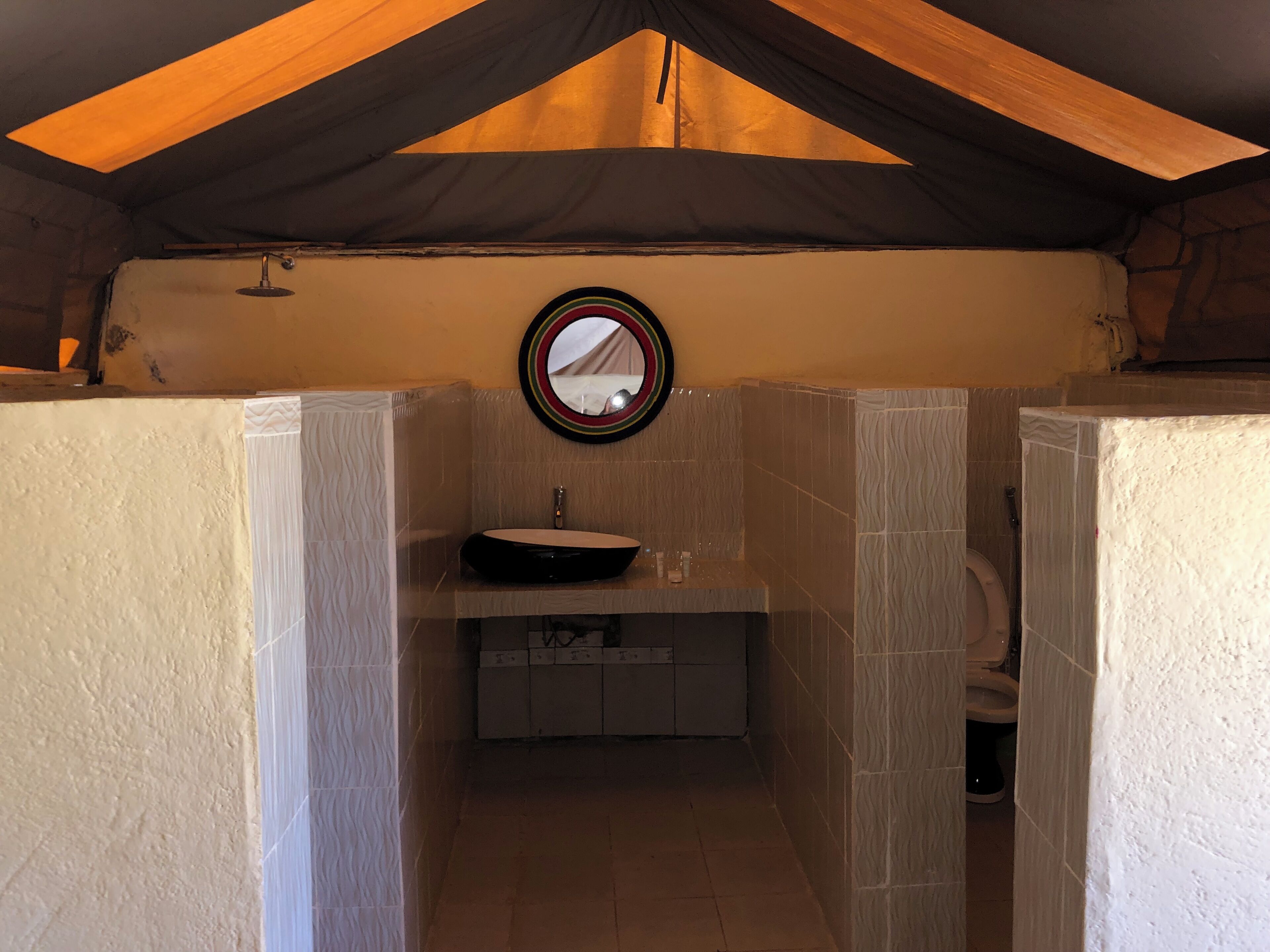 Un baño pequeño con un espejo redondo, un lavabo e inodoro.
