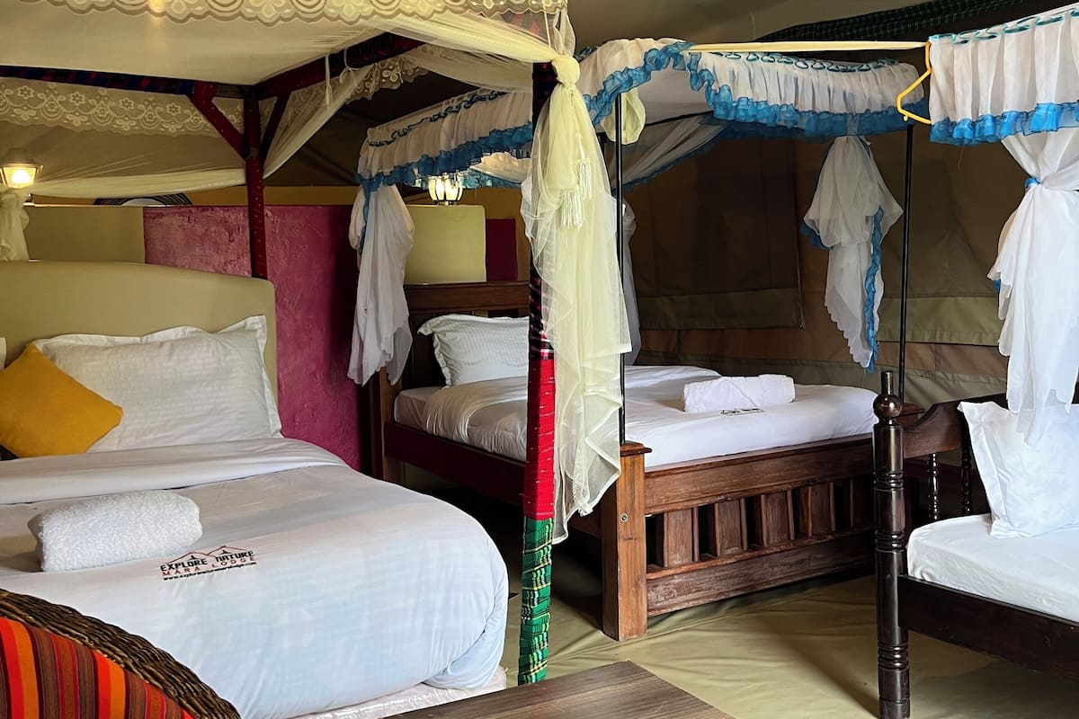 A room with two beds, a wooden table, and a wicker chair.