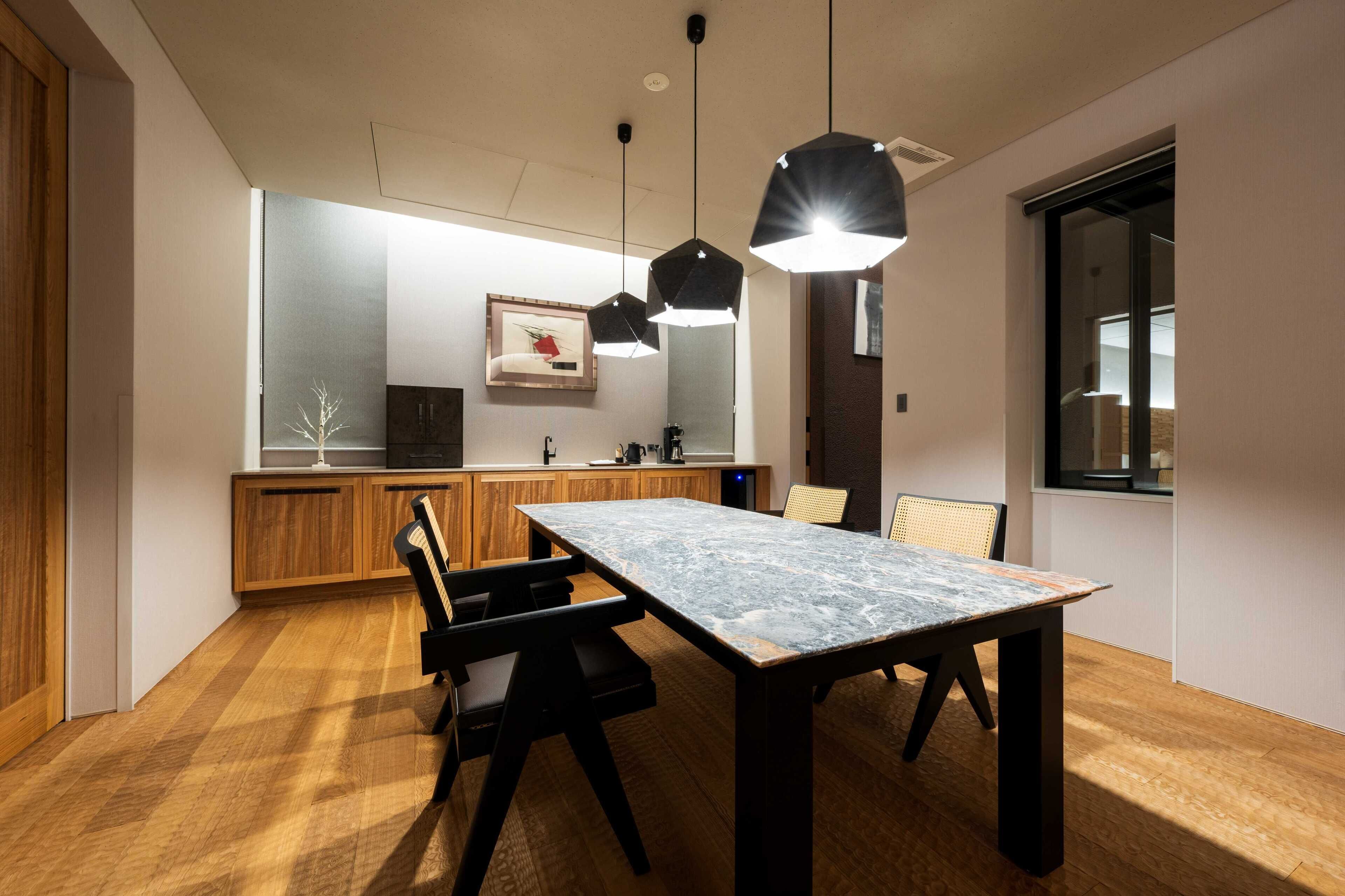 A modern kitchen with wooden cabinets, a marble countertop, and pendant lighting.