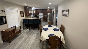 Una cocina compacta con electrodomésticos modernos, una zona de comedor con una mesa redonda y sillas, además de un banco.