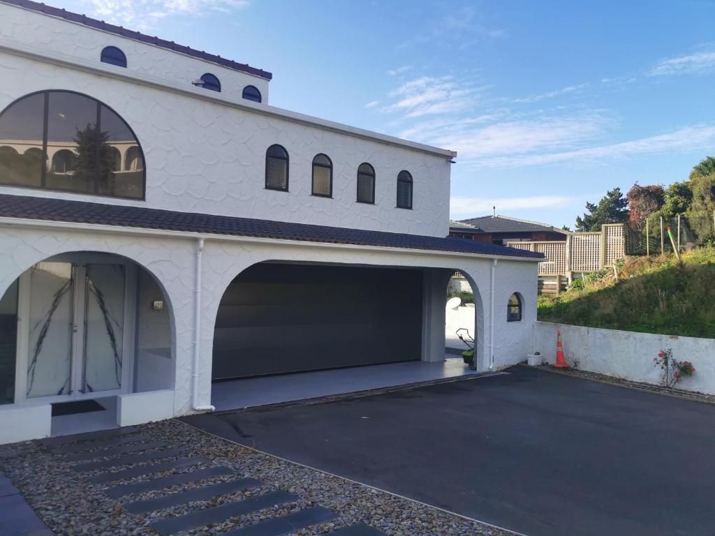 A two-story building with a garage door, large windows, and a sloped roof.