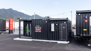 Un conteneur transformé en hôtel, avec une enseigne indiquant « The Yard » et « R9 Hotels Group ».