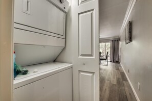 A laundry room with a door leading to a hallway with a dining area.