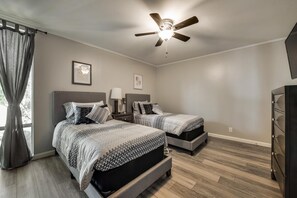 A bedroom with two beds, a ceiling fan, and a dresser.