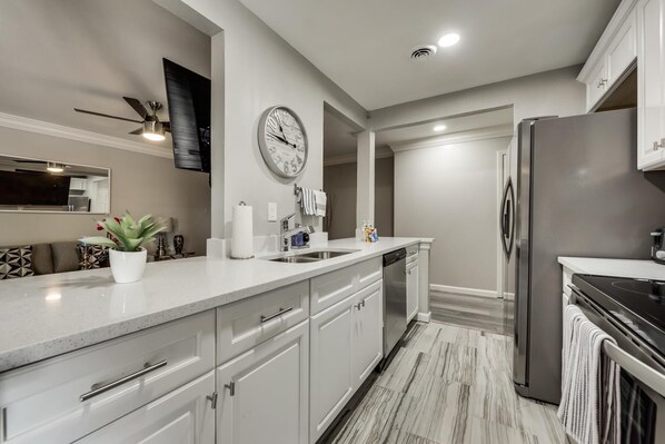 A modern kitchen with a large island, stainless steel appliances, and a clock on the wall.