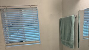 A bathroom with a toilet, sink, and window with blinds. - Villa by Eco-shared (Miami)